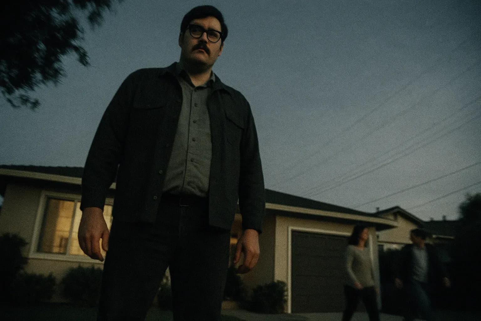 A figure resembling Edmund Kemper stands outside a suburban California house, towering ominously with a vacant stare, while neighbors pass by unaware, symbolizing the hidden horrors lurking beneath the surface.