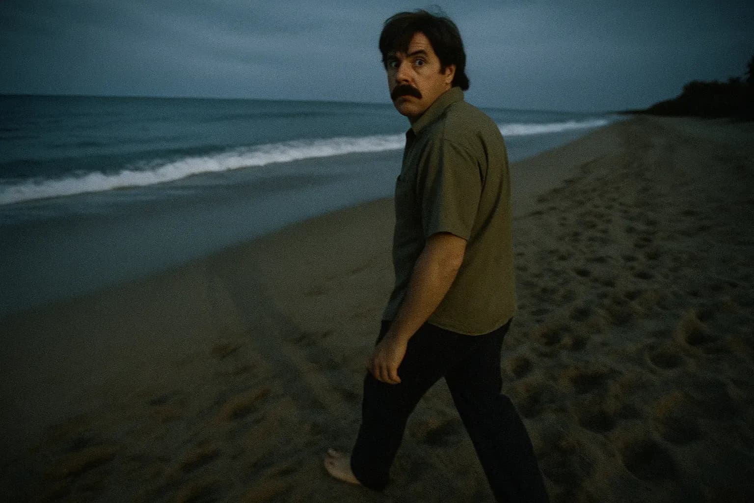 A figure resembling David Ghantt walks alone on a Mexican beach, looking over his shoulder, the ocean meeting the horizon behind him, symbolizing his escape after the Loomis Fargo heist