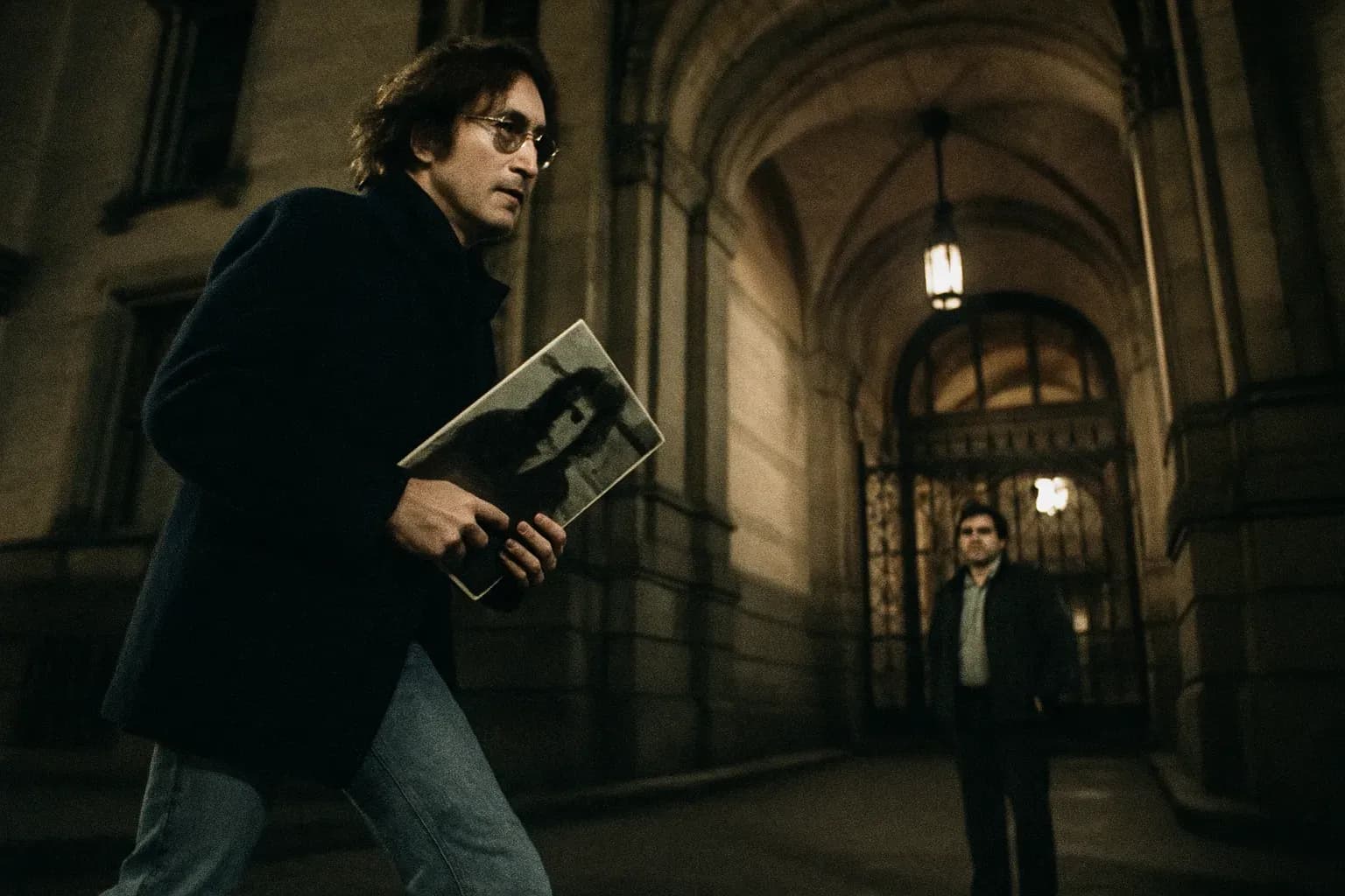 A figure resembling John Lennon walks near the Dakota building entrance, holding a record album, unaware of Mark David Chapman waiting nearby.